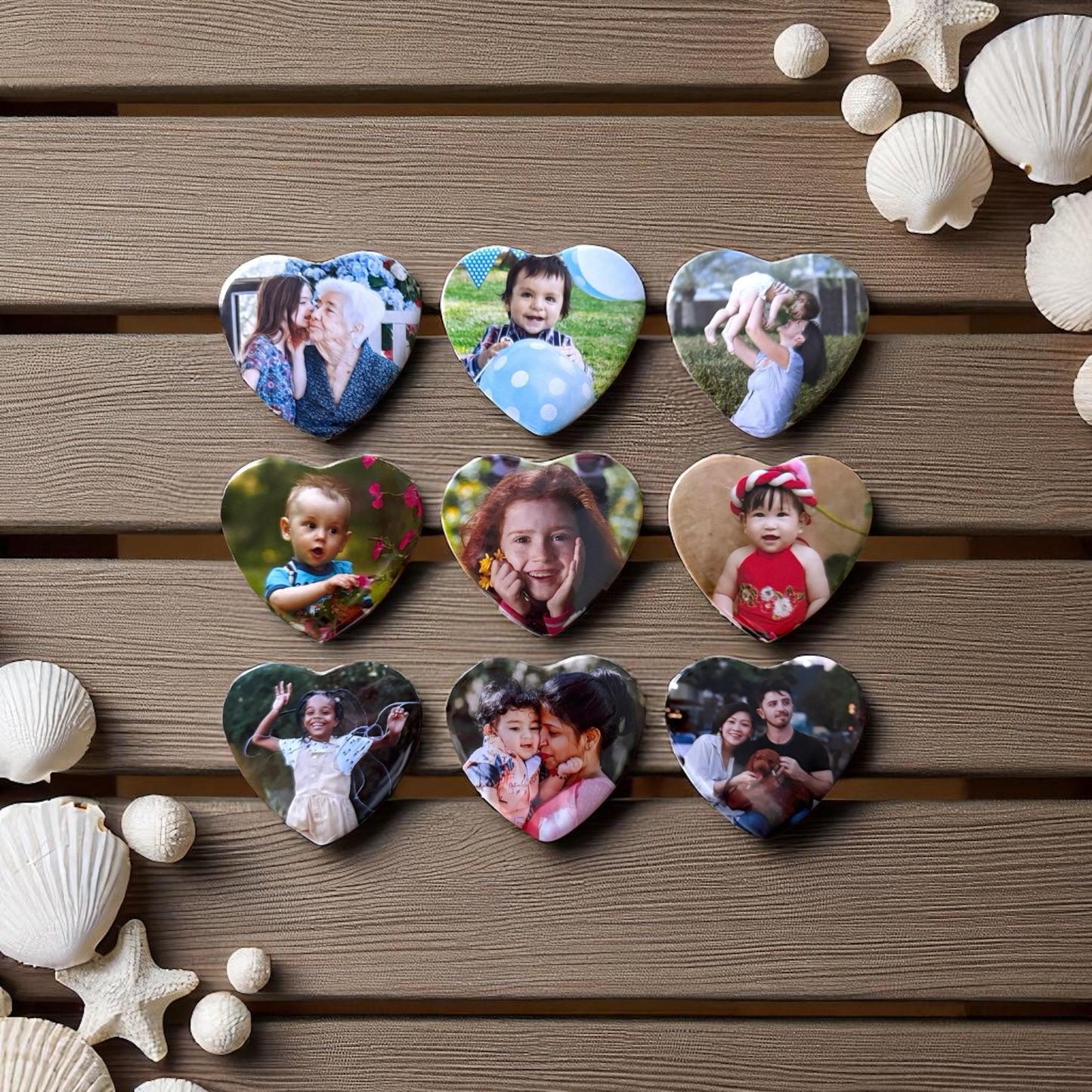 Collection of heart-shaped photo magnets with various images on a wooden surface with seashells and starfish.