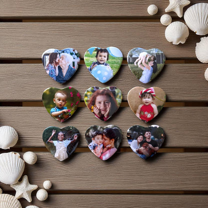 Collection of heart-shaped photo magnets with various images on a wooden surface with seashells and starfish.