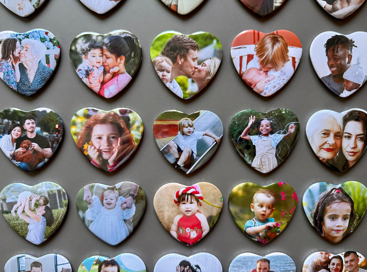 Collection of heart-shaped photo magnets with various images on a gray background